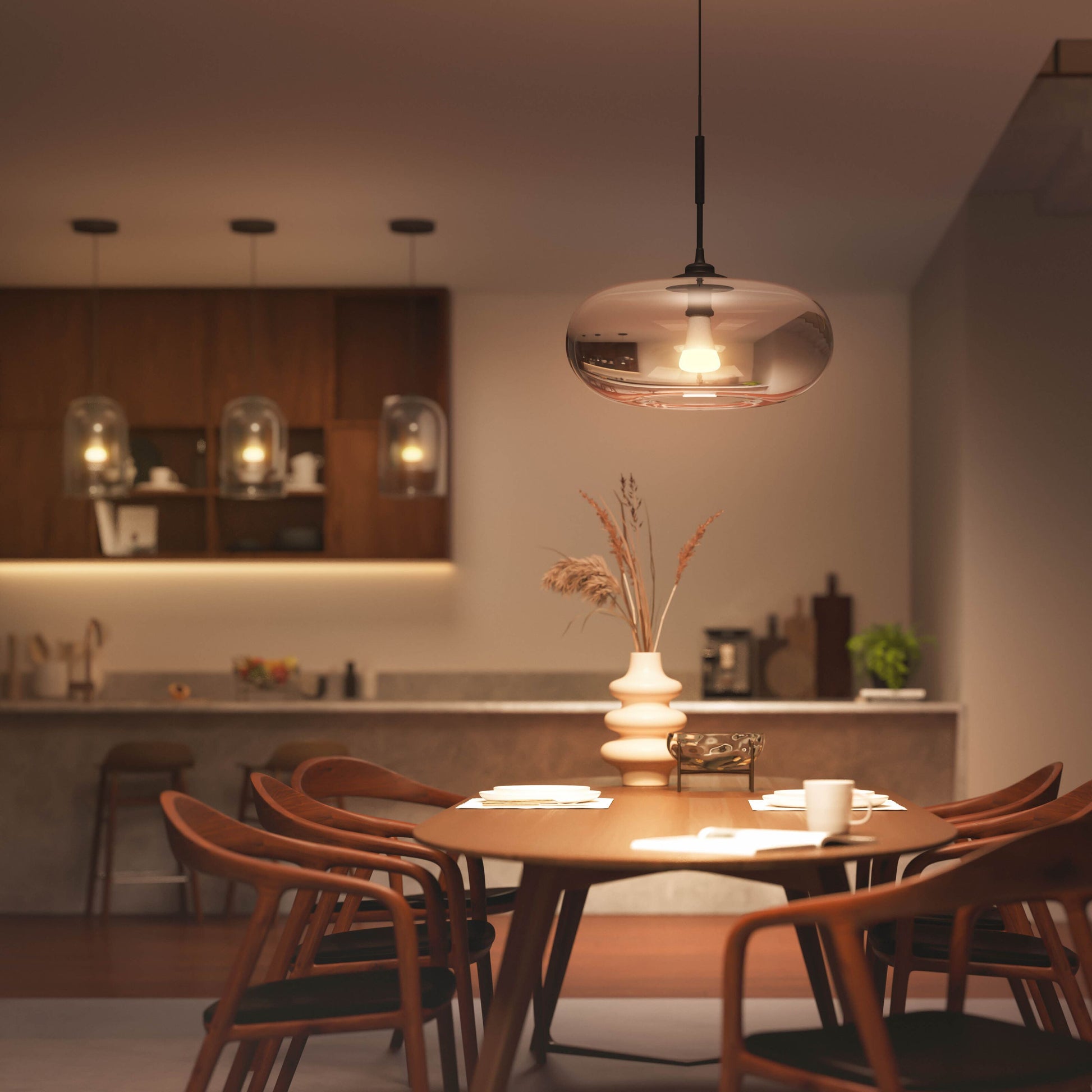 Hue Color Ambiance Smart LED-pære E27 1600 lm i pendel over rundt spisebord med fem stole og hvid vase med tørrede græsser.