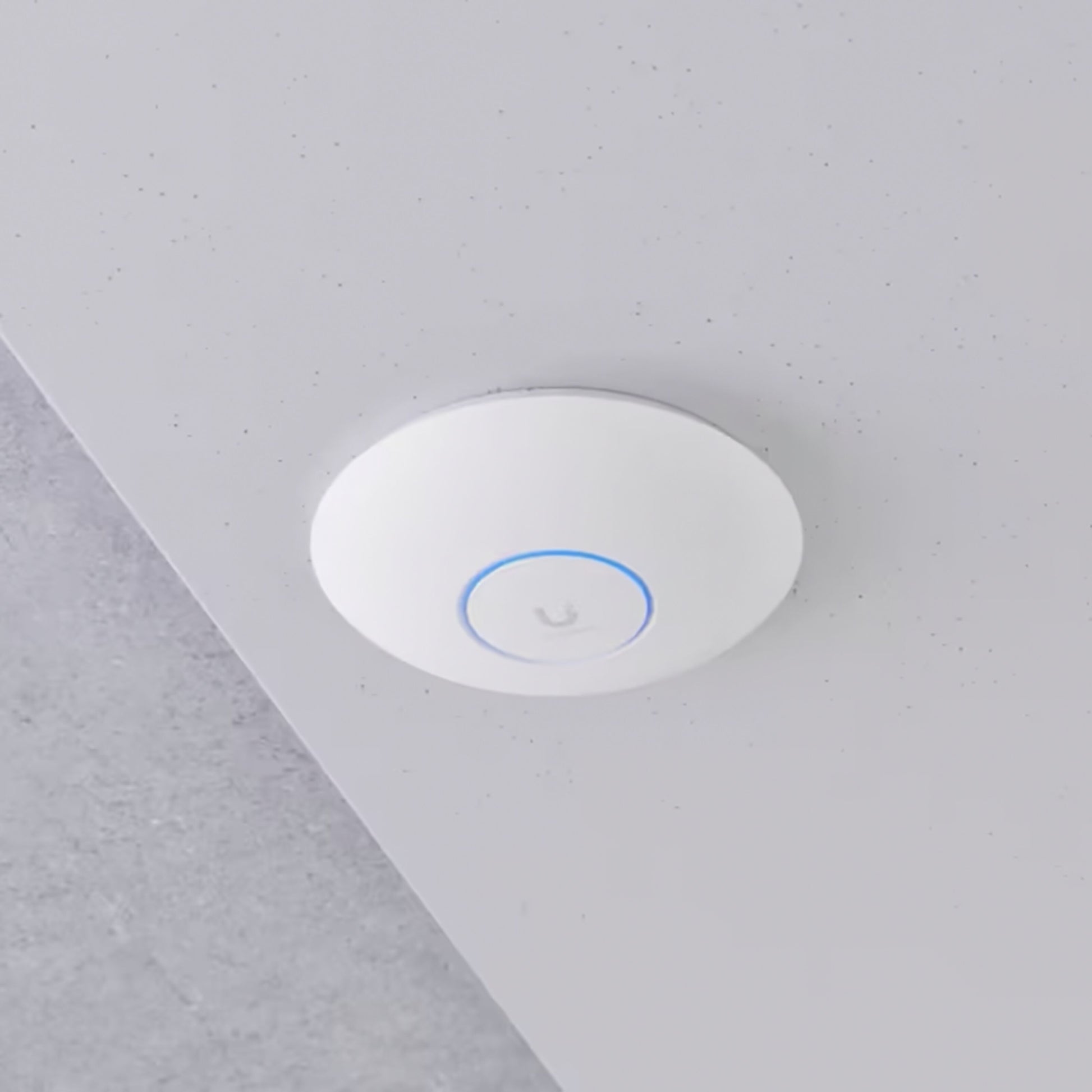 Ubiquiti Unifi U7 Pro hvidt rundt adgangspunkt med Wifi 7 og diskret blå LED-ring monteret på lysegråt loft.