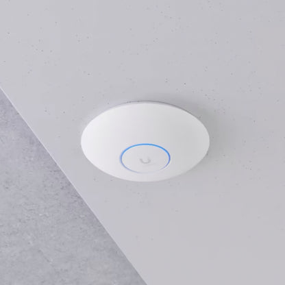 Ubiquiti Unifi U7 Pro hvidt rundt adgangspunkt med Wifi 7 og diskret blå LED-ring monteret på lysegråt loft.
