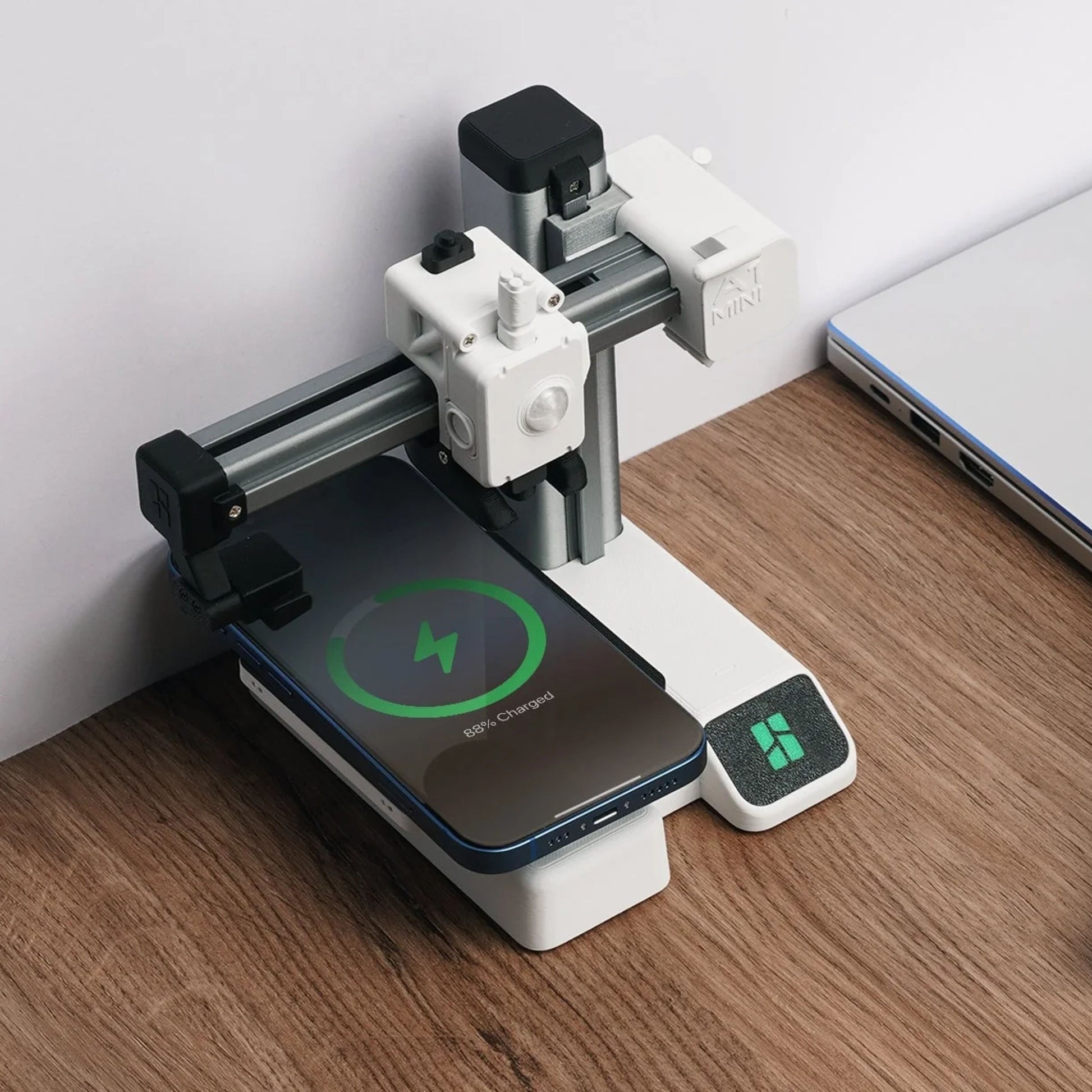 Bambu Lab 3D-sæt til trådløs oplader ved laptop, smartphone med grøn opladeikon, CNC-maskine i baggrunden.