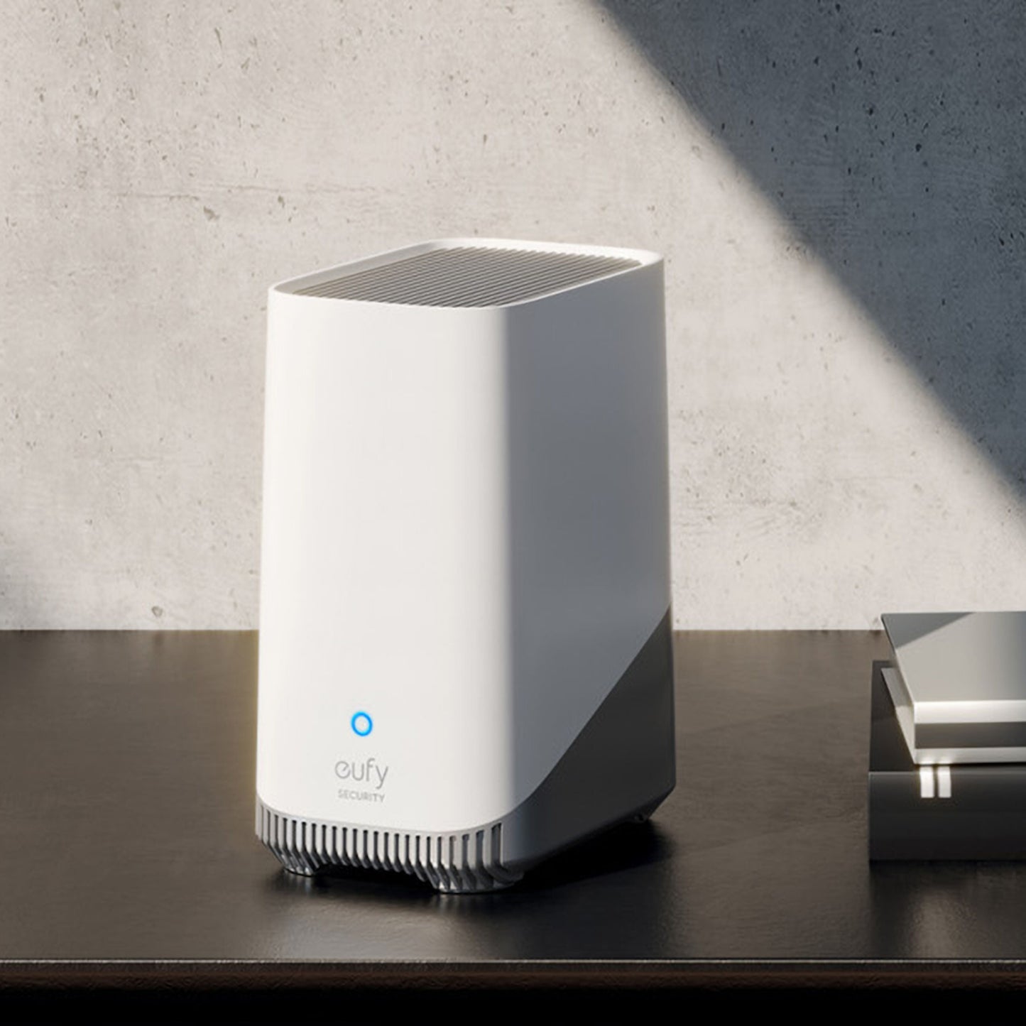 Eufy S380 HomeBase 3 16 GB hjemmesikkerhedssystem med blåt lys, lokal lagring, på mørk overflade ved betonvæg.
