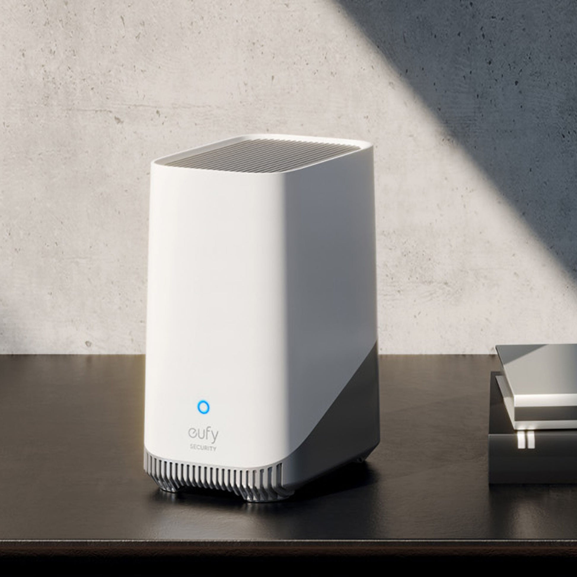 Eufy S380 HomeBase 3 16 GB hjemmesikkerhedssystem med blåt lys, lokal lagring, på mørk overflade ved betonvæg.