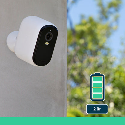 Arlo Essential 2K XL overvågningskamera 2-pakke på væg i sort og hvid, batteriikon med 2 års levetid, grønne træer baggrund.