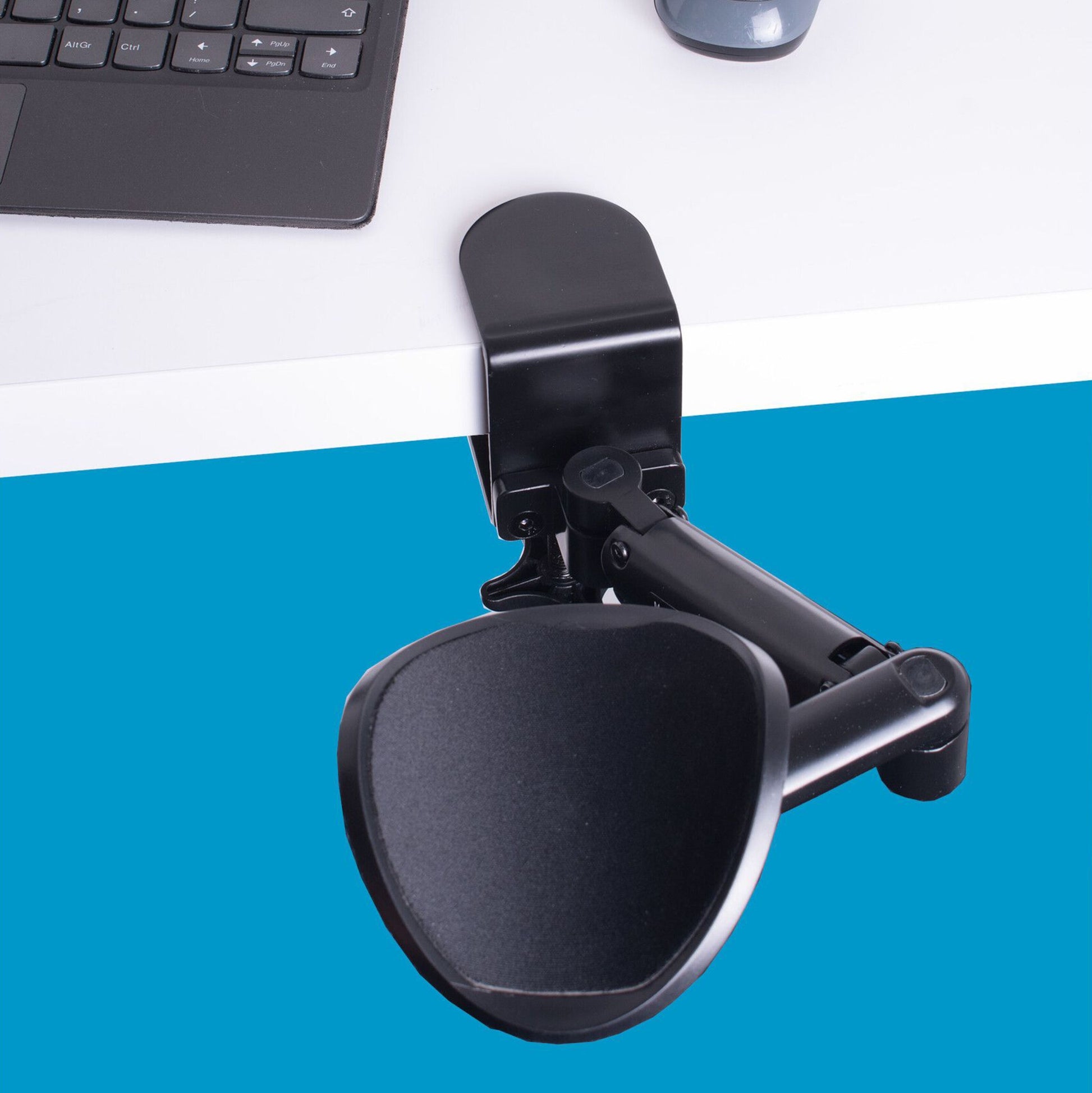Desire2 MouseMate musestøtte og ergonomisk armlæn monteret på skrivebord ved bærbar pc, blå baggrund.