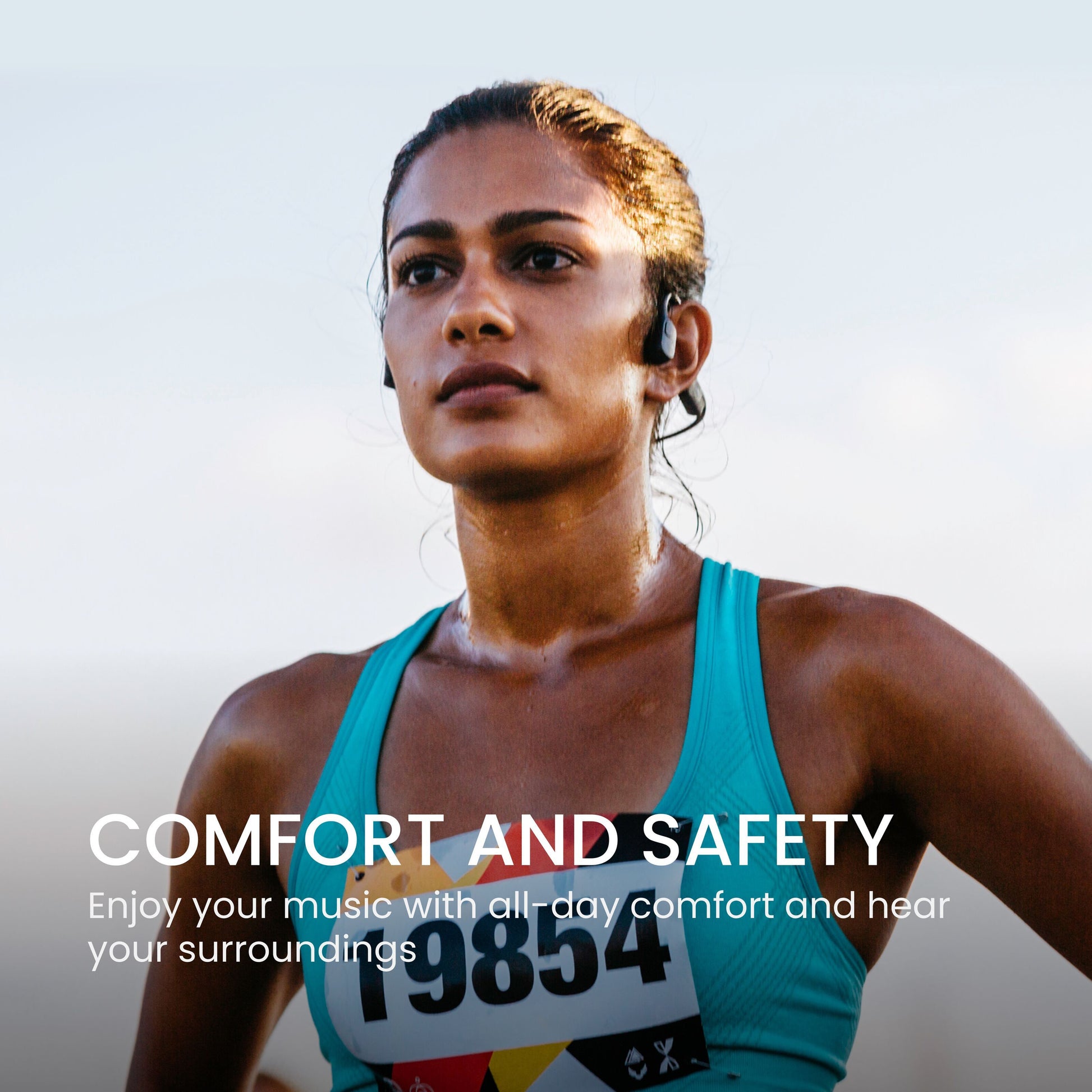 Shokz OpenRun Mini trådløse øretelefoner USB-C på kvindelig løber med startnummer, tekst: Komfort og sikkerhed.