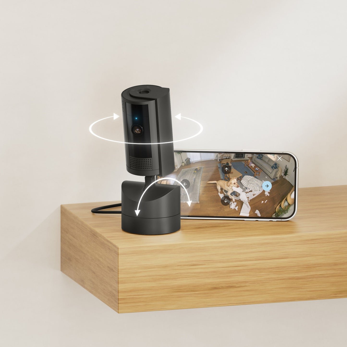 Ring Pan-Tilt Indendørs Kamera sort, viser roterende 360°, smartphone viser live 1080p HD video af rum med hund.