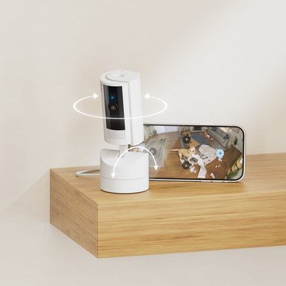 Ring Pan-Tilt indendørs kamera på bord ved smartphone med live-feed, viser 360° rotation og farve nattesyn.
