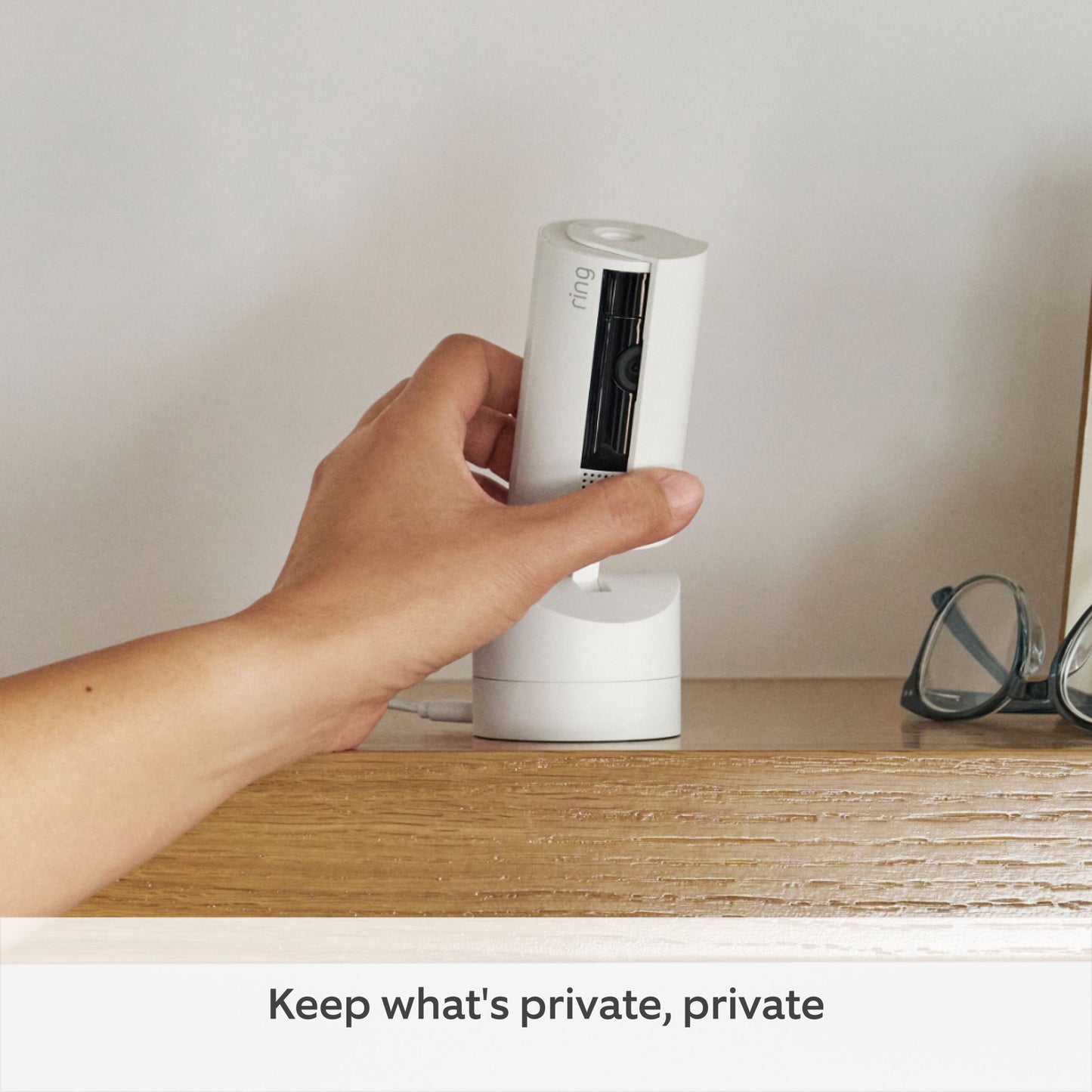 Ring Pan-Tilt indendørs kamera hvid på træhylde ved briller, tekst: Keep what's private, private, tilbyder farve-nattesyn.