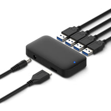 Sort USB 3.0 hub 4-vejs med fire tilsluttede USB-kabler, strømforsyningskabel, datakabel og lille blå indikatorlysdiode.