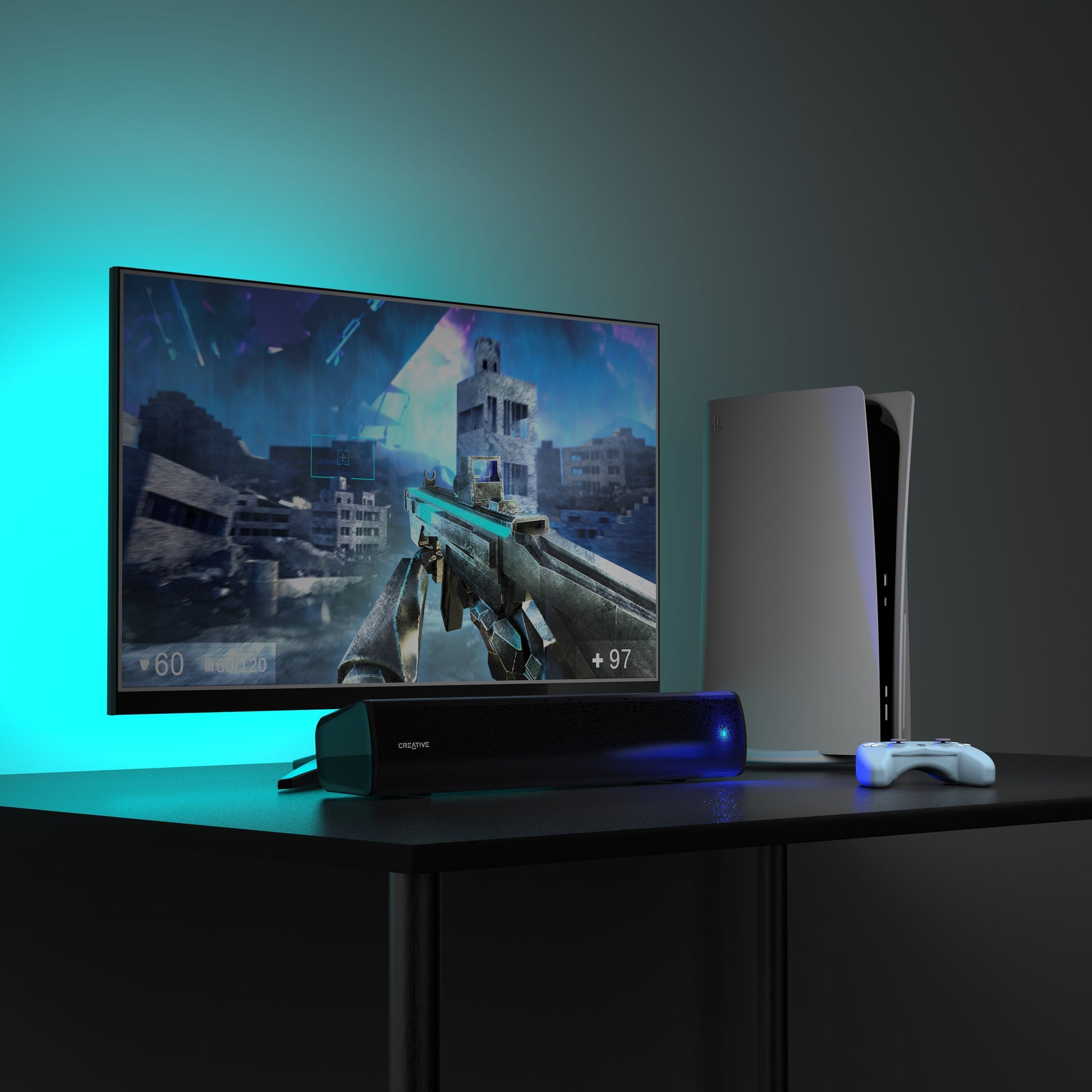 PlayStation 5 konsol, trådløs controller og Scene Air V2 Bluetooth soundbar på sort bord med blåt ambient lys.