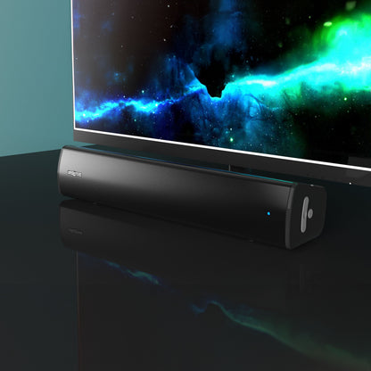 Creative Scene Air V2 sort Bluetooth soundbar med blå indikatorlys på blank sort overflade under tv med rum-motiv.
