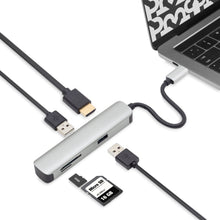 A Plexgear USB-C Multiadapter - 5 porte is connected to a laptop, offering HDMI, USB, and memory card slots. Multiple devices and cables are plugged into the hub for expanded connectivity.