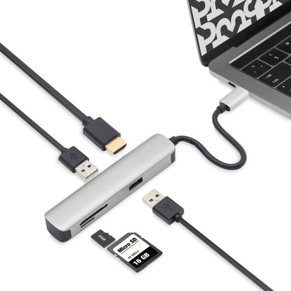 A Plexgear USB-C Multiadapter - 5 porte is connected to a laptop, offering HDMI, USB, and memory card slots. Multiple devices and cables are plugged into the hub for expanded connectivity.