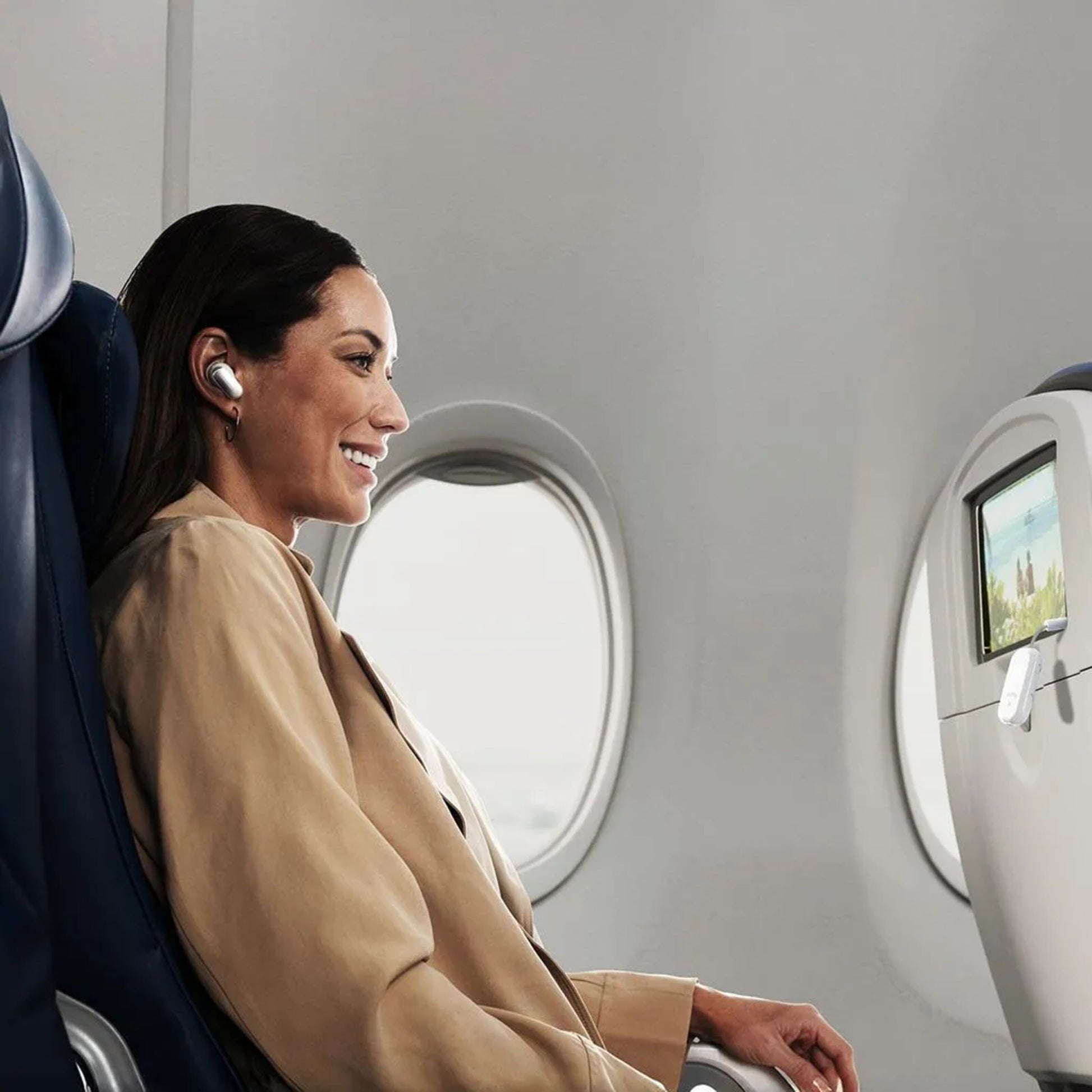 AirFly Pro 2 Bluetooth-sender og -modtager bruges med ørepropper, vises i brug på flysæde ved siden af vinduer.