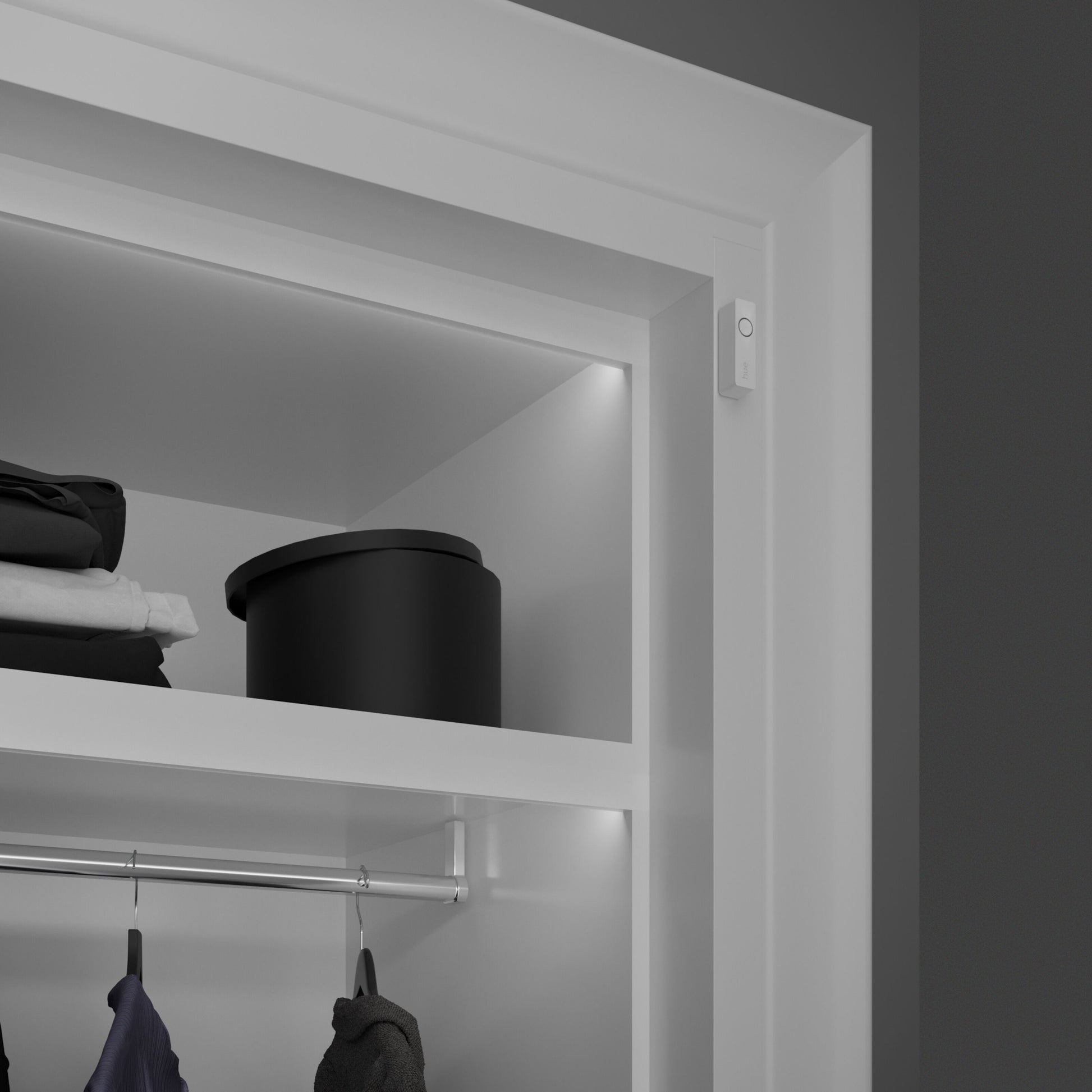 Philips Hue Sikker kontakt sensor Hvid 1-pak monteret i hvidt skab med tøj og sort opbevaringsboks, integreret lys.