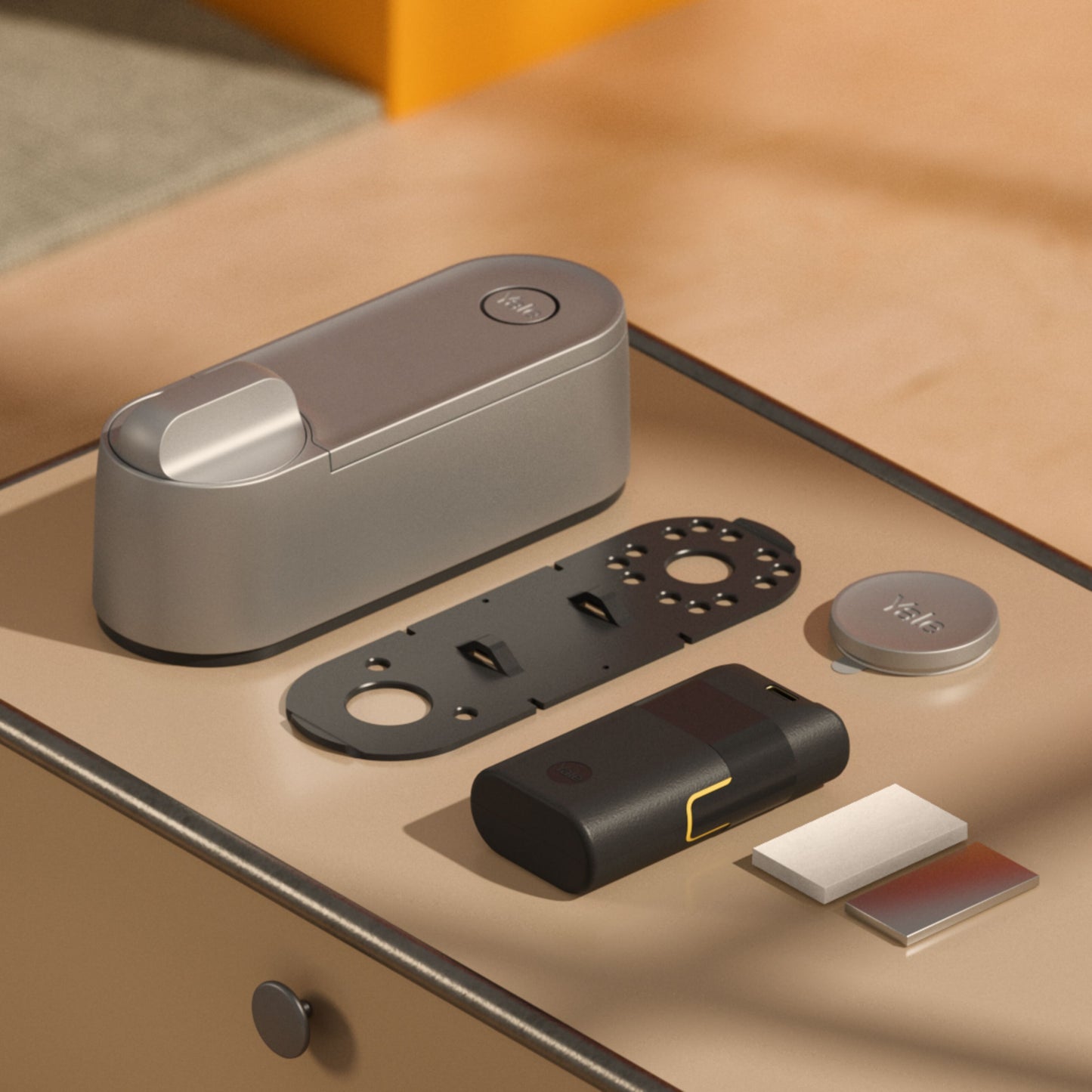 Yale Linus Smart Lock L2 sølv med genopladeligt batteri, monteringsplade, rund dækskive og selvklæbende strips.