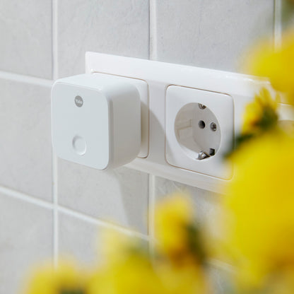 Yale ConnectX Wi-Fi smart plug i stikdåse ved flisevæg, synlig sort/hvid model, smart home kontekst.