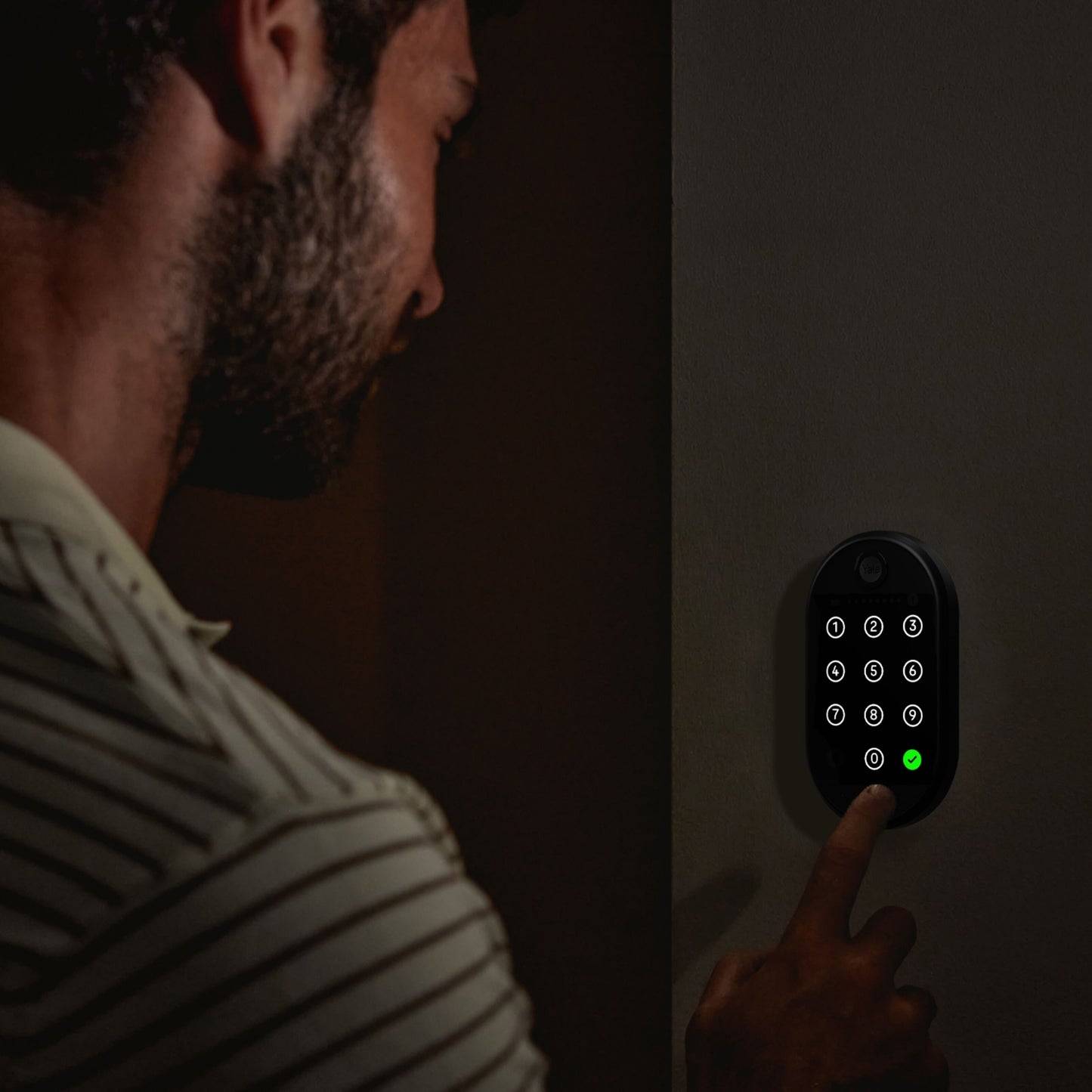 Yale Smart tastatur 2 fingeraftryk med grøn lysindikator for adgang, person indtaster kode.