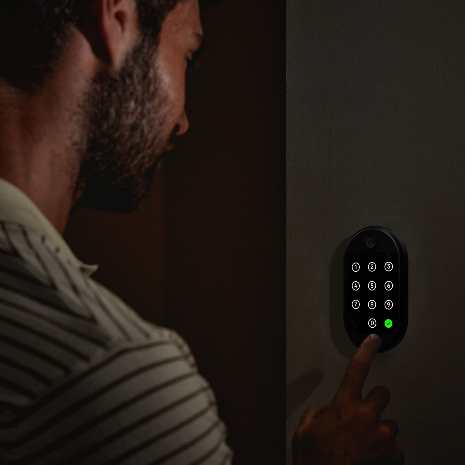 Yale Smart tastatur 2 fingeraftryk med grøn lysindikator for adgang, person indtaster kode.