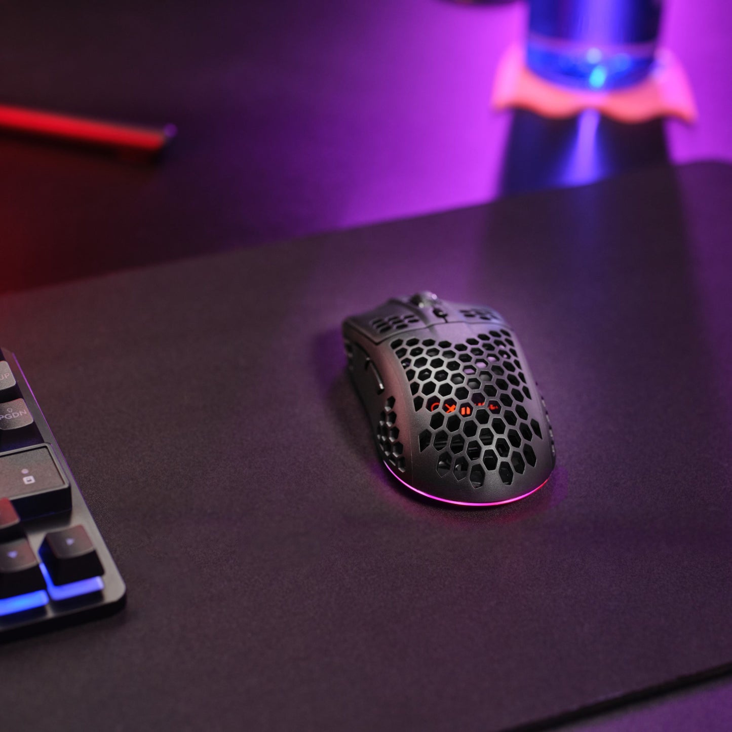 Trust Helox GXT929 trådløs gamingmus sort, honeycomb-design, justerbar 800-4800 DPI ved siden af tastatur med farvet lys.
