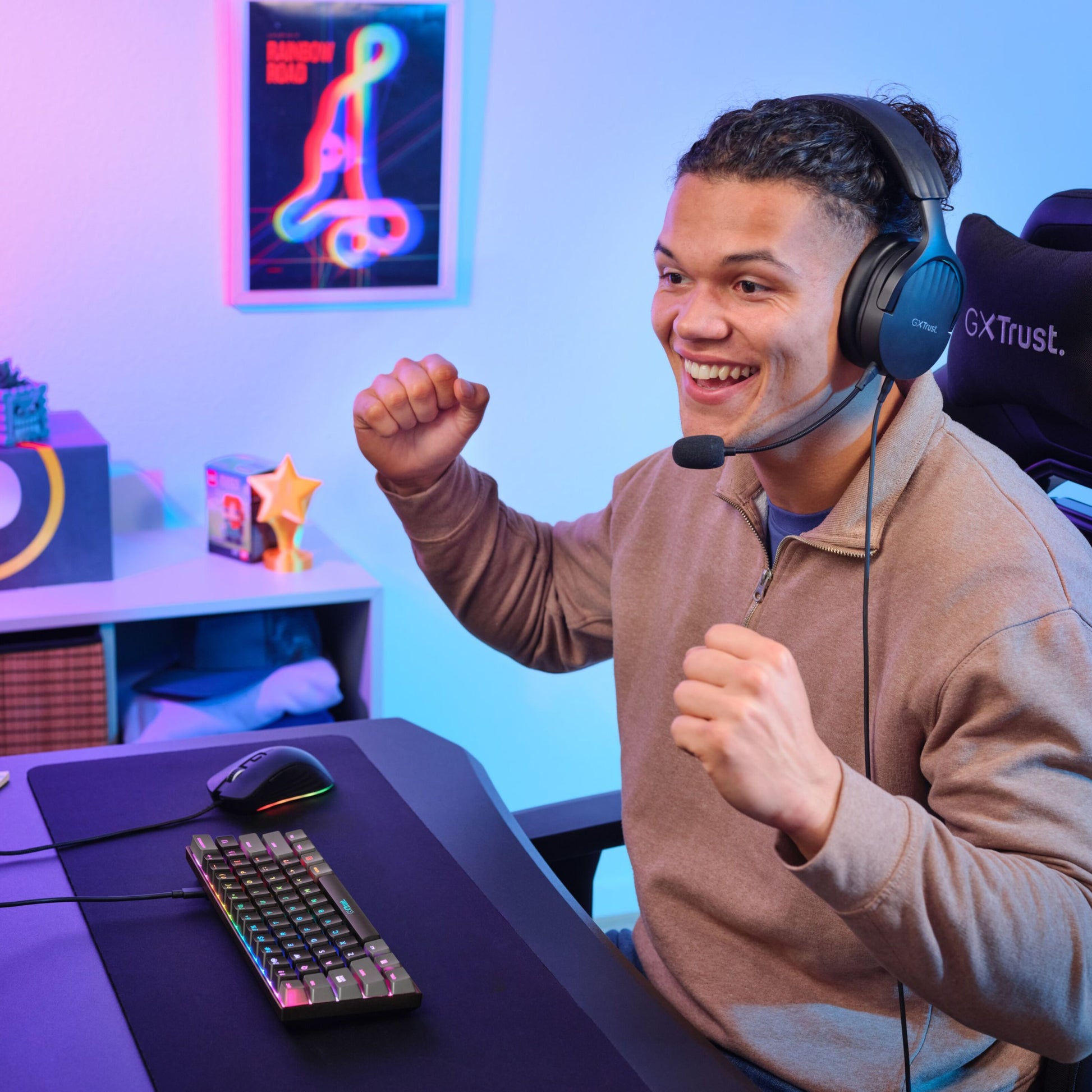 Person med headset ved skrivebord bruger Trust Acira GXT867 Tastatur 60 gaming chair og hylder i baggrunden.