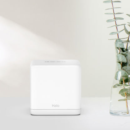 Mercusys Halo H60X Mesh Wifi 6-system 2-pak i hvid, kubeformet, på lys flade, synlig vase med grønne eukalyptusgrene.