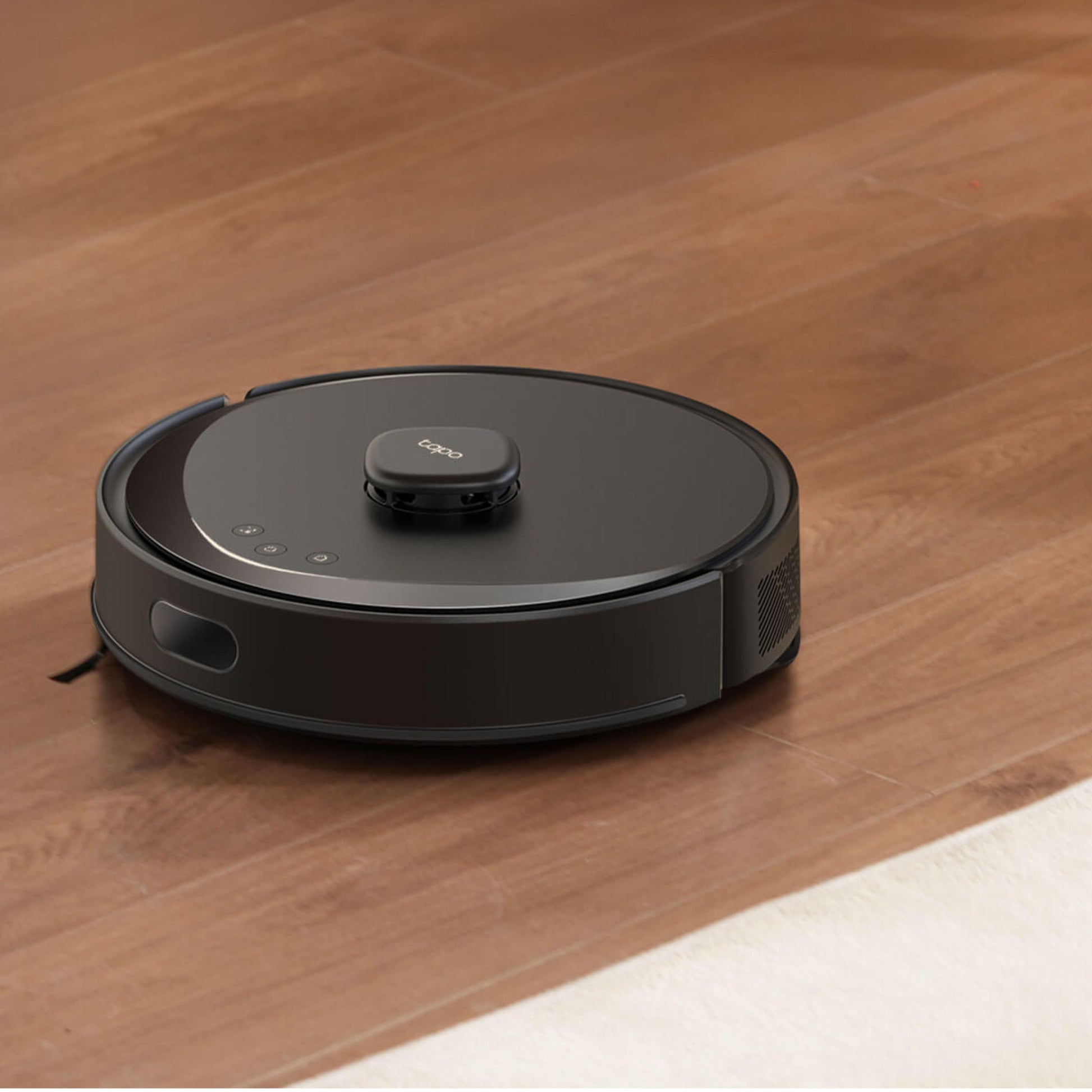 TP-Link Tapo RV30 Max robotstøvsuger på trægulv ved siden af hvidt tæppe.