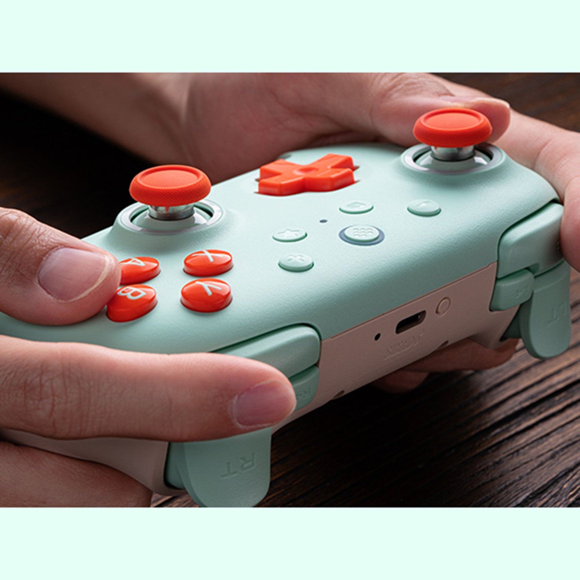 8Bitdo Ultimate 2C trådløs håndkontrol med Hall Effect, mintgrøn og hvid med orange knapper og joysticks.