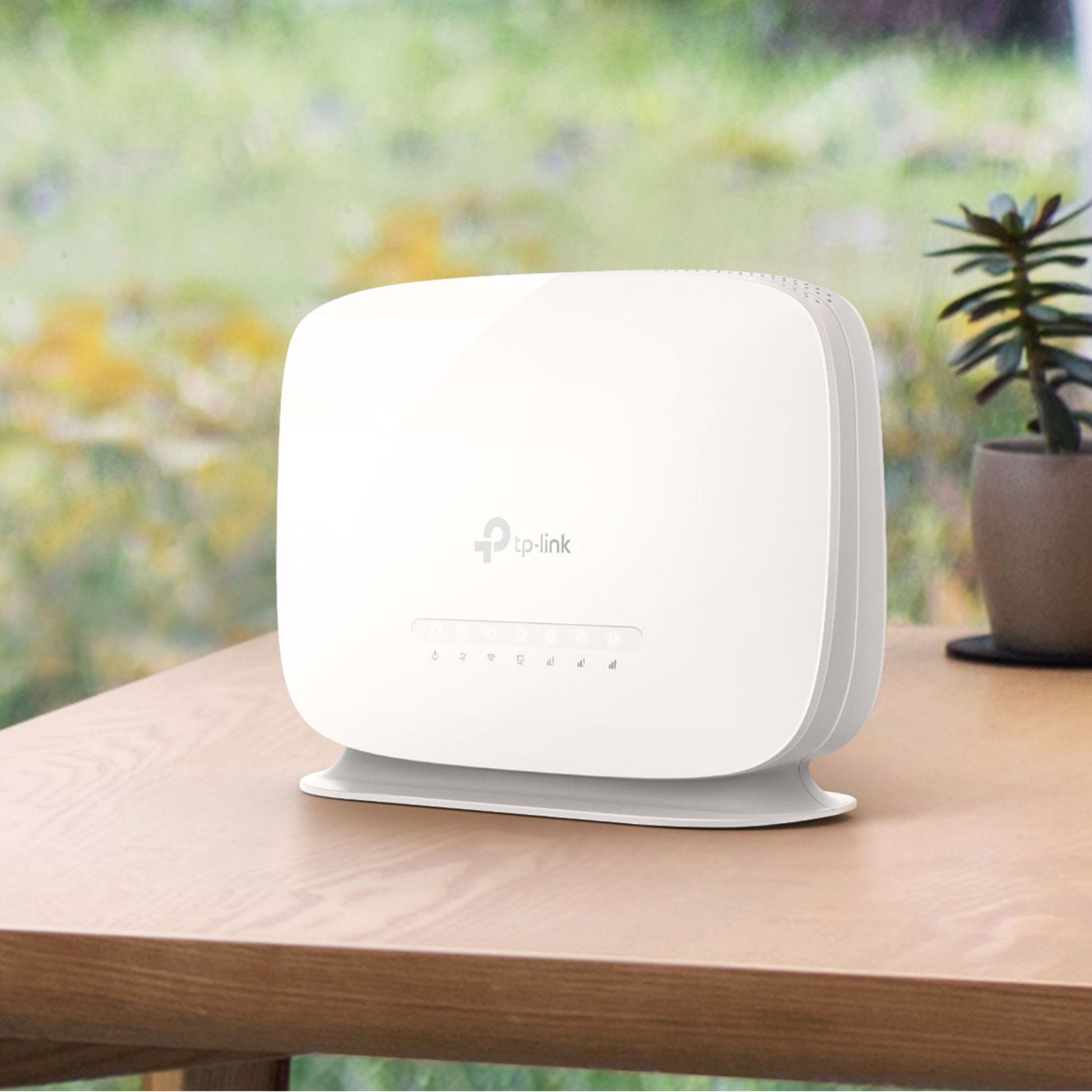 TP-Link Archer MR515 4G+ router med modem AC1200 sort står på bord ved vindue, lille potteplante ved siden af.