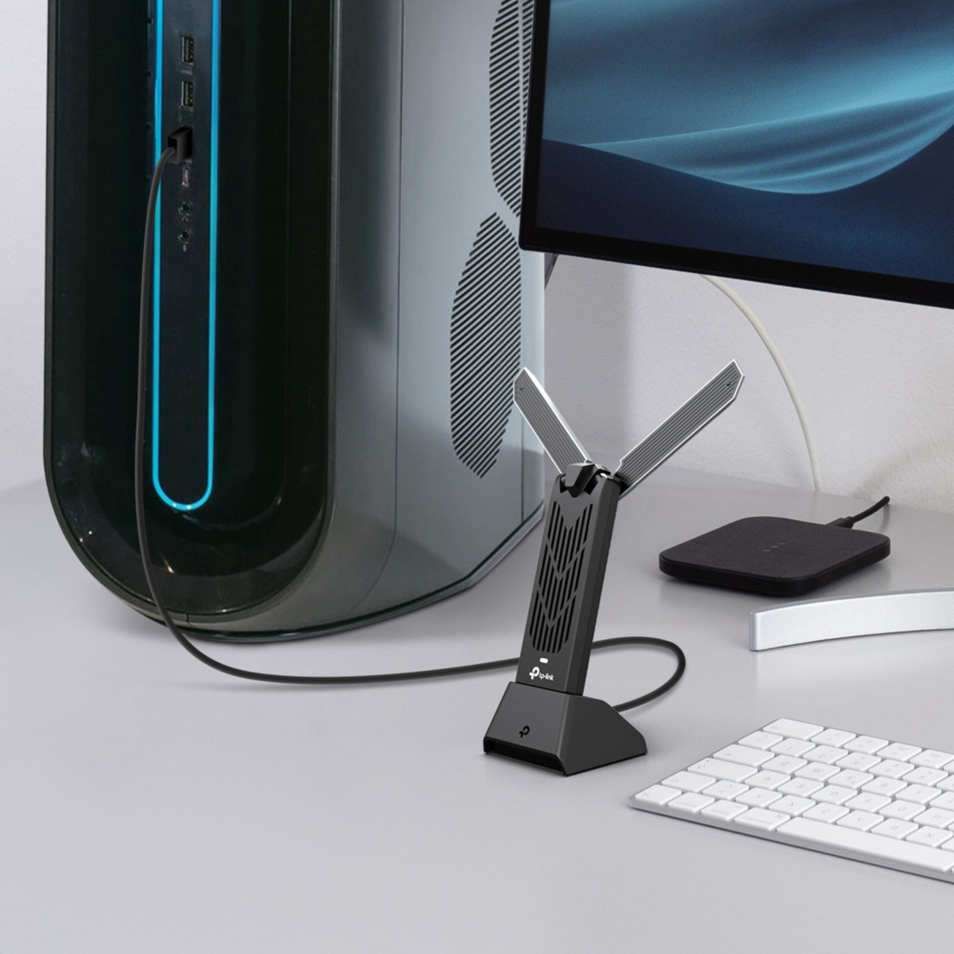 TP-Link Bueskytte TBE400UH WiFi 7 USB-adapter med to antenner tilsluttet stationær pc ved tastatur, mus og skærm.