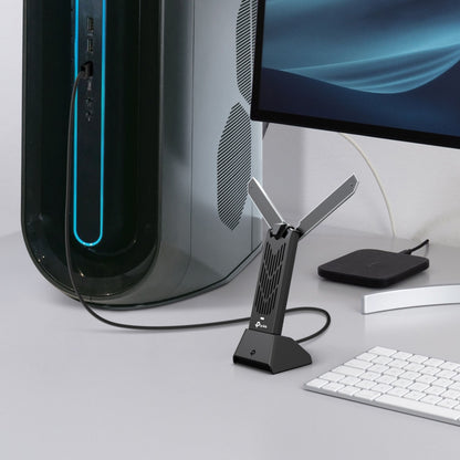 TP-Link Bueskytte TBE400UH WiFi 7 USB-adapter med to antenner tilsluttet stationær pc ved tastatur, mus og skærm.