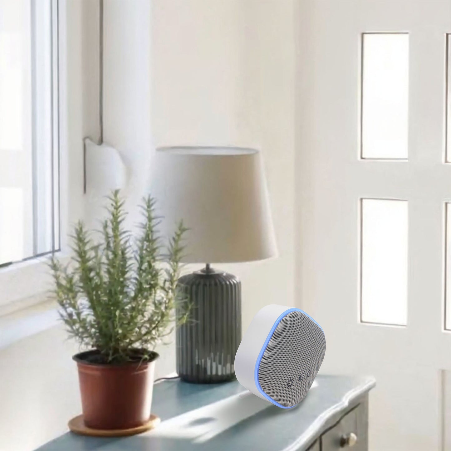 Cleverio Trådløs dørklokke med trykknap på bord ved højtaler, urtepotte og lampe i sollys.