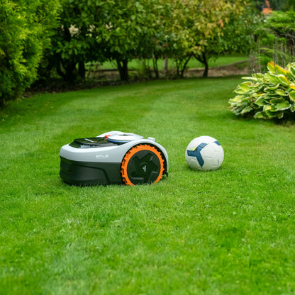 Segway Navimow i105e robotplæneklipper til 500 m² ved hvid og blå fodbold mellem grønne buske og planter.