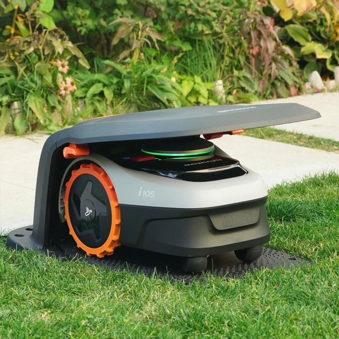 Segway Navimow i105 robotplæneklipper på græs under Segway Garage S1A02E til i105 og i208E AWD, planter og flisegang.