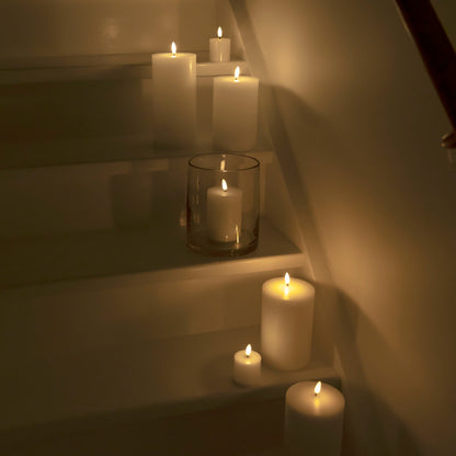 Bloklys LED 3-pakke placeret på hvide trapper langs kanten, lyser med blødt, varmt lys i et dæmpet rum.