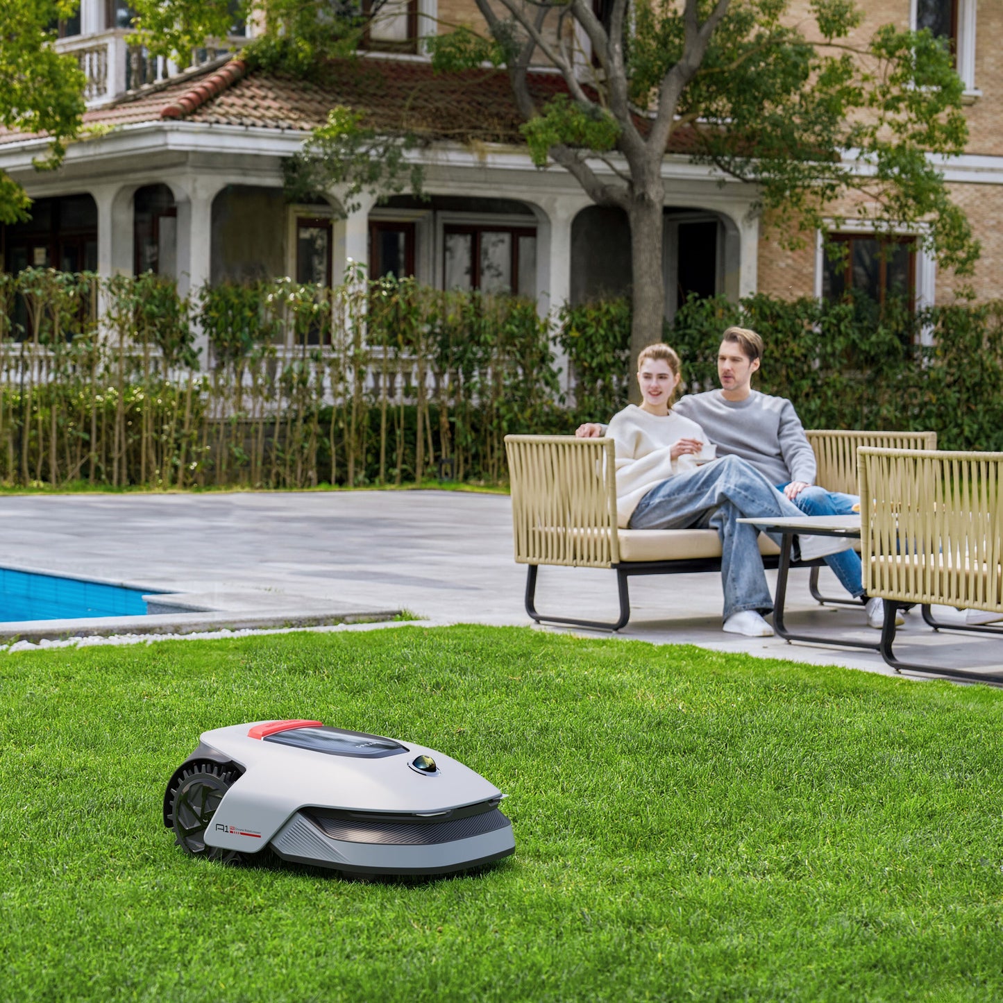 Dreame A1 Pro robotplæneklipper klipper græs i baghave nær pool og udendørsmøbler med smilende par.