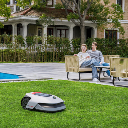 Dreame A1 Pro robotplæneklipper klipper græs i baghave nær pool og udendørsmøbler med smilende par.