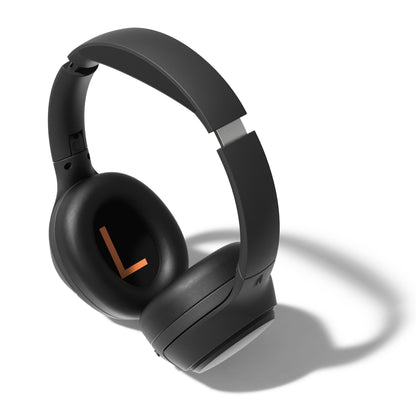 Nomadelic Solo 750 trådløse ANC-hovedtelefoner, sort med metalliske detaljer og stor orange L på venstre ørekop.