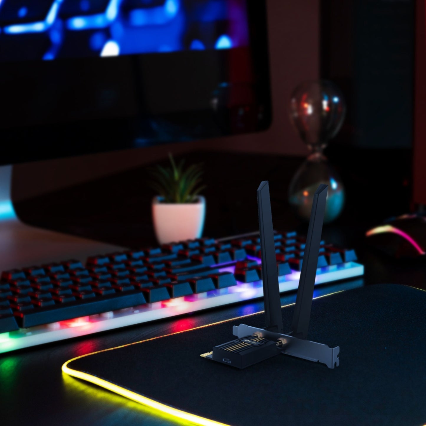 TP-Link Archer TBE400E Wi-Fi 7 PCIe netværkskort med to antenner på RGB-musemåtte foran bagbelyst tastatur og skærm.