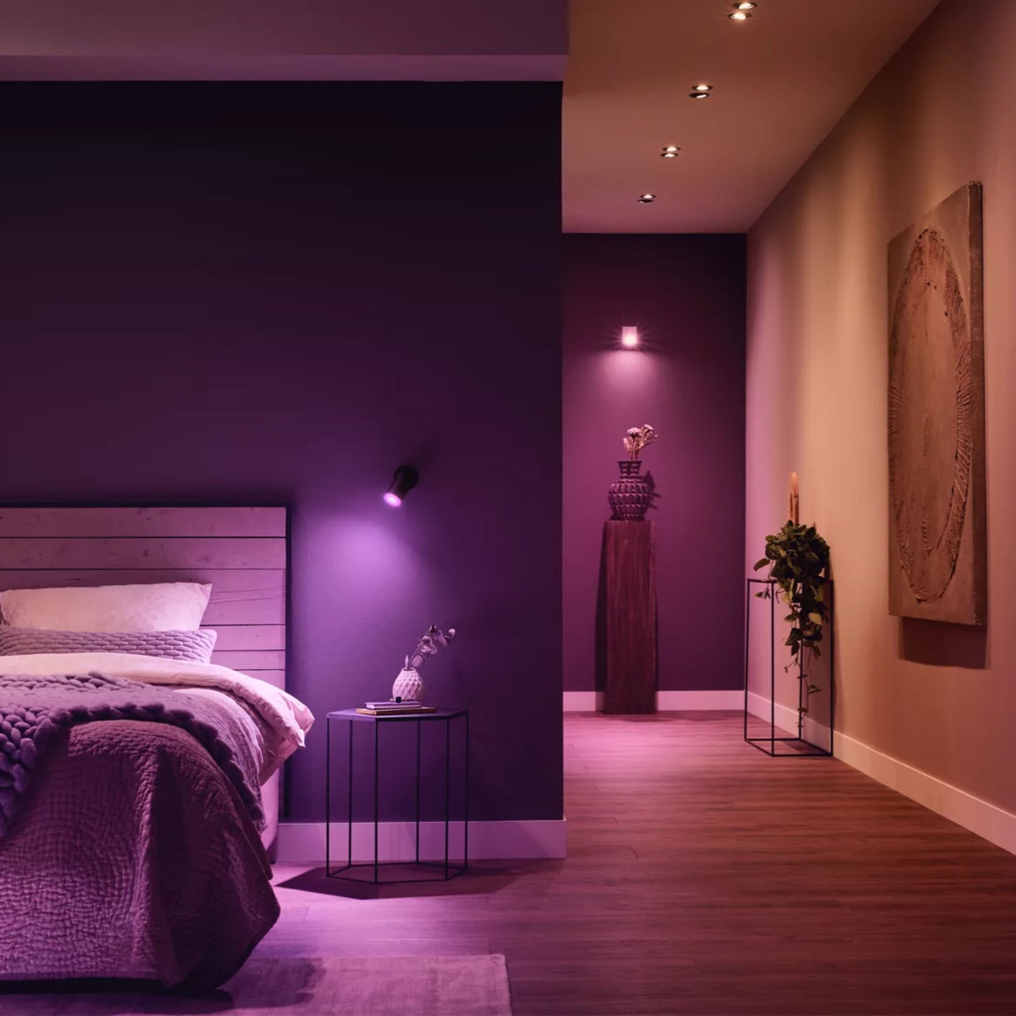 Philips Hue White and Color Ambiance 3x GU10 Smart Startpakke lilla lys i soveværelse med træseng og natbord.