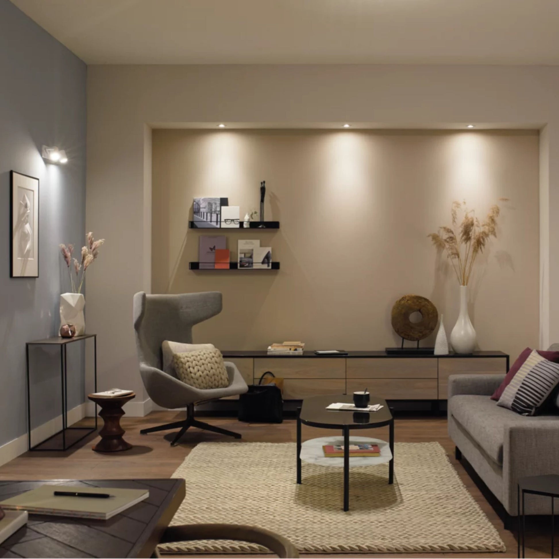Philips Hue GU10 400 lm smart LED-pærer 2-pak Hvid Ambiance synlig i moderne stuemiljø med grå stol og beige tæppe.