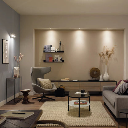 Philips Hue GU10 400 lm smart LED-pærer 2-pak Hvid Ambiance synlig i moderne stuemiljø med grå stol og beige tæppe.