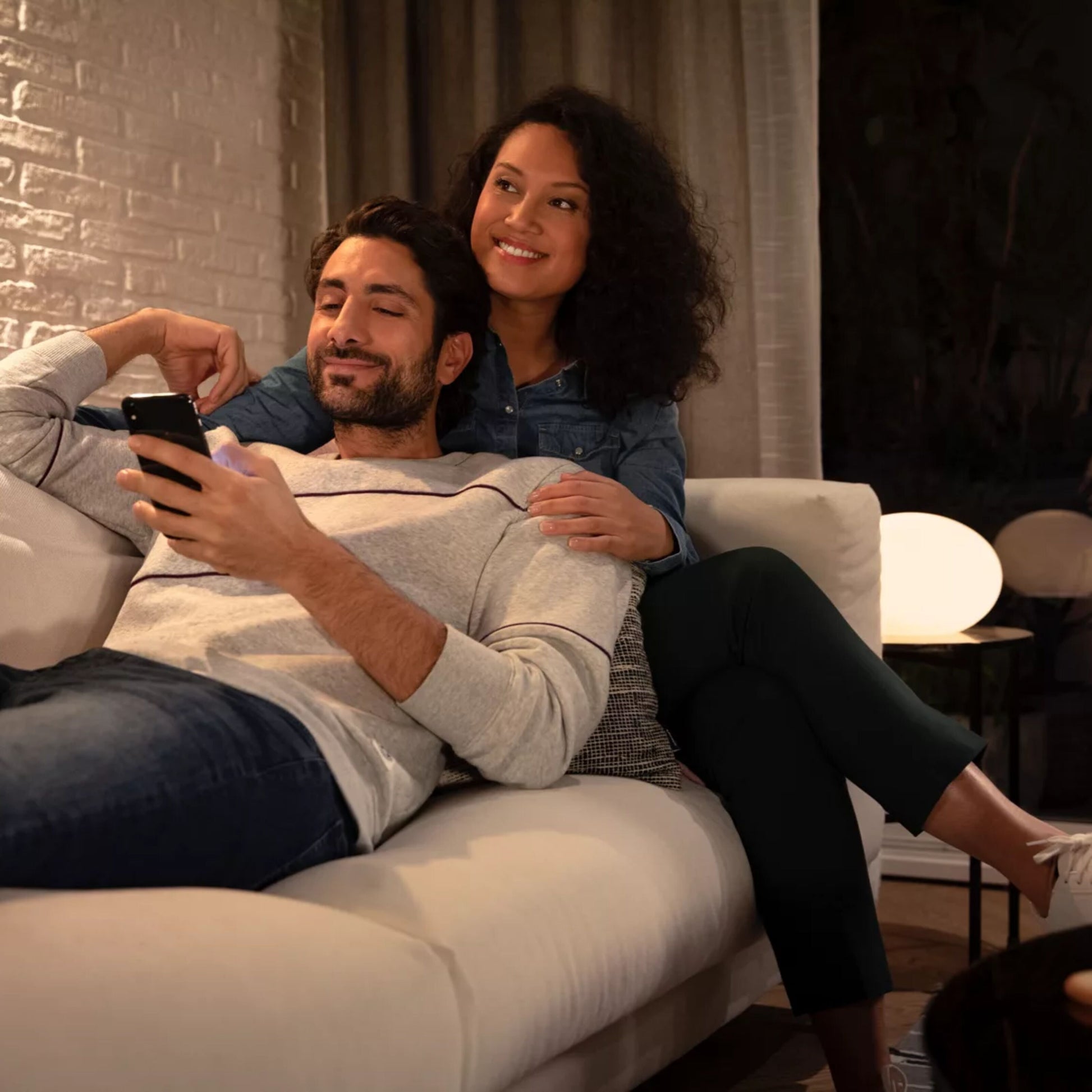 Hue Hvid Ambiance Smart LED-pære GU10 400 lm 2-pak oplyser stuen, par på hvid sofa i baggrunden.
