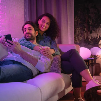 Hue Hvid og farve ambiance smart LED-pære GU10 400 lm 2-pak lyser stue op i pink og lilla nuance, par på sofa.