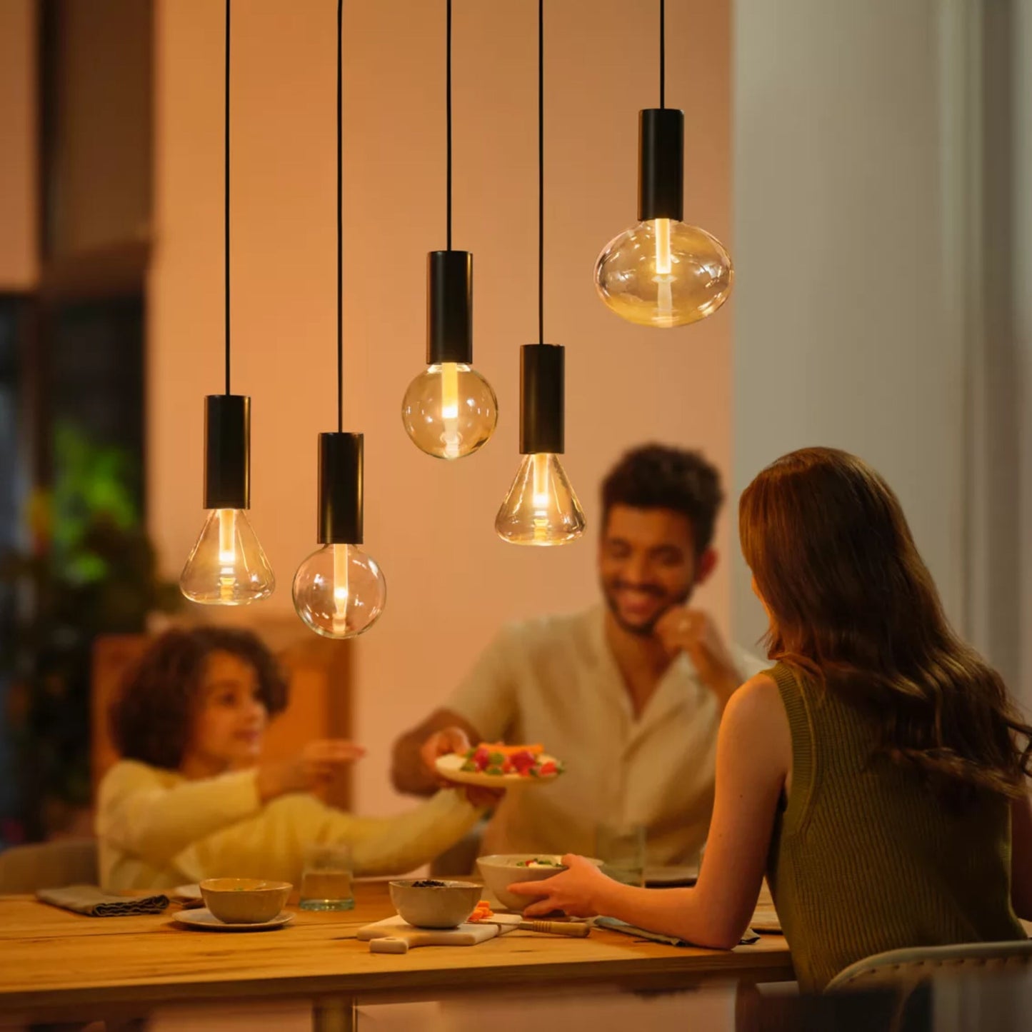 Philips Hue Lightguide G125 E27 smart LED-pære glob 500 lm i pendellamper over spisebord med personer.