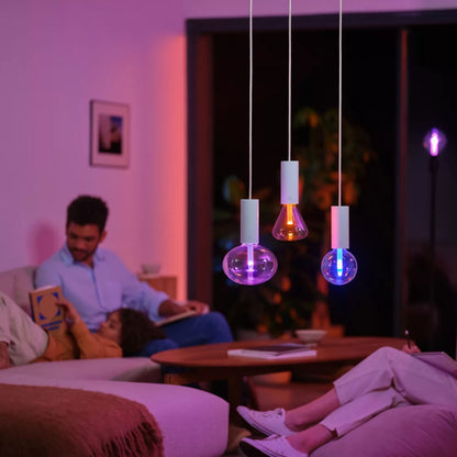 Philips Hue Lightguide G125 E27 smart LED-pærer i farver tændt i stue, personer sidder i sofa og stol.