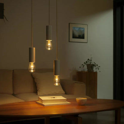 Philips Hue RGB ST72 smart LED-pære E27 500 lm i pendel, synlig over sofabord med bog og kop, beige sofa.