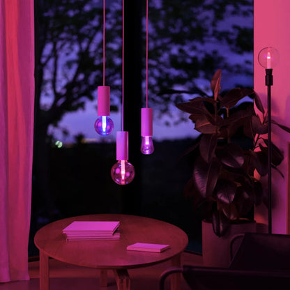Philips Hue RGB ST72 smart LED-pære E27 500 lm, tre stk. i lilla og blå belysning, synlig plante og bøger.