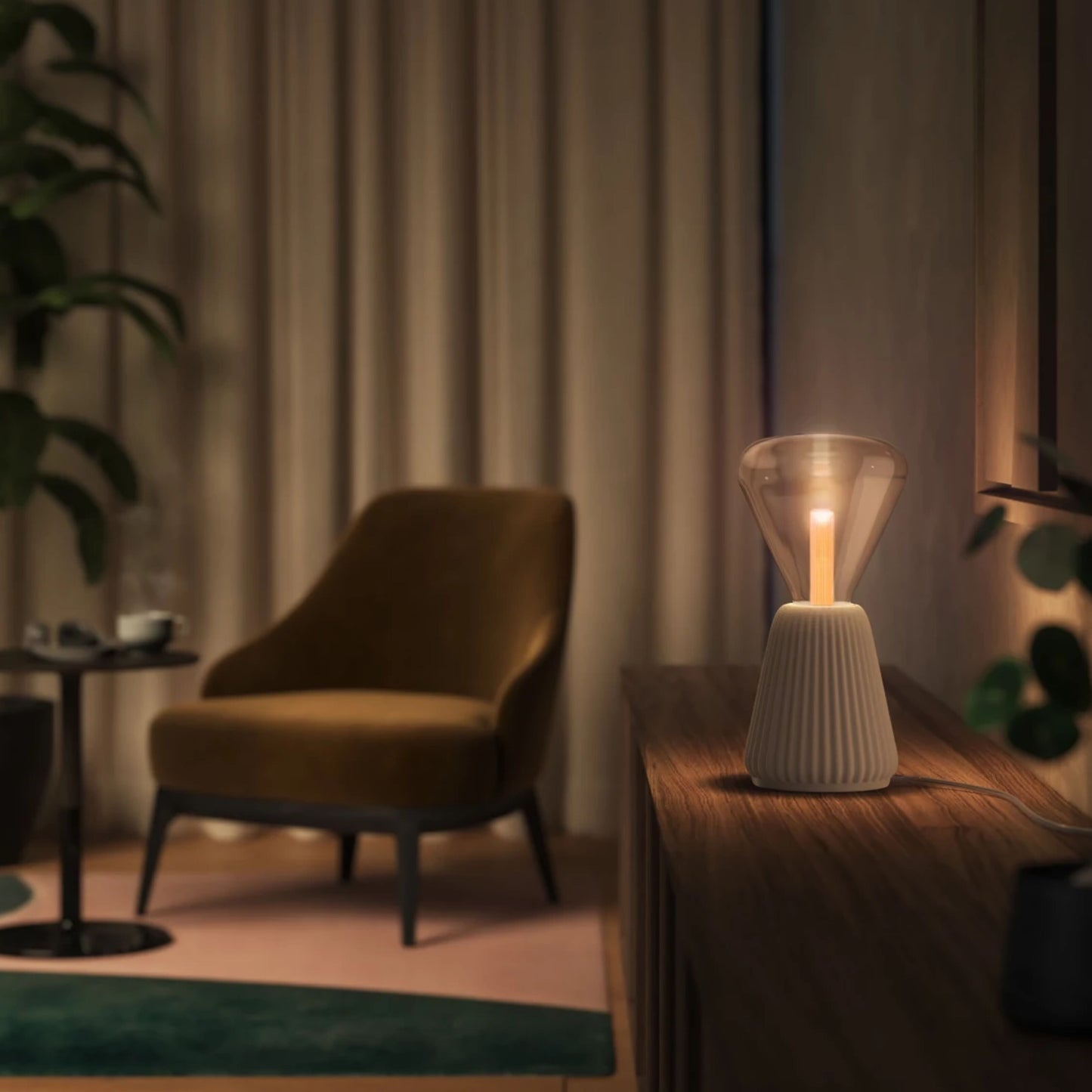 Philips Hue Lightguide Triangle E27 smart LED-pære 500 lm på træskab foran beige gardiner og grønne planter.