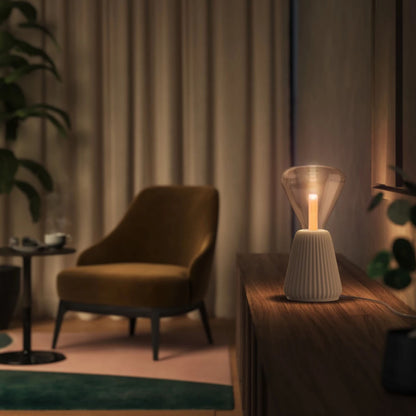 Philips Hue Lightguide Triangle E27 smart LED-pære 500 lm på træskab foran beige gardiner og grønne planter.